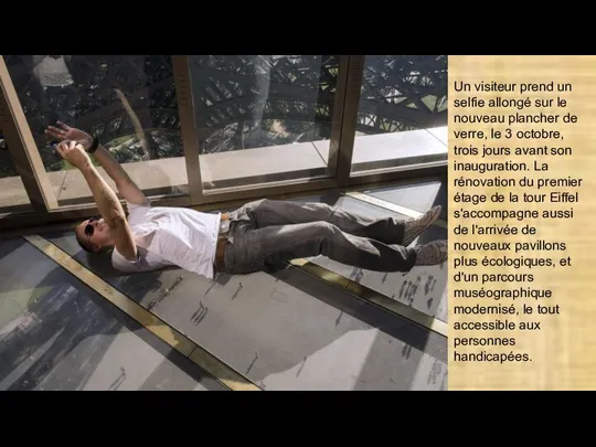Un visiteur prend un selfie allongé sur le nouveau plancher de verre,