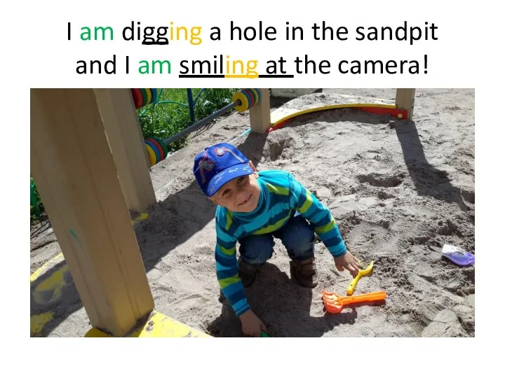 I am digging a hole in the sandpit and I am smiling at the camera!