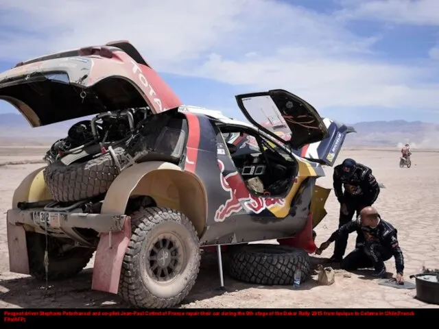 Peugeot driver Stephane Peterhansel and co-pilot Jean-Paul Cottret of France repair their